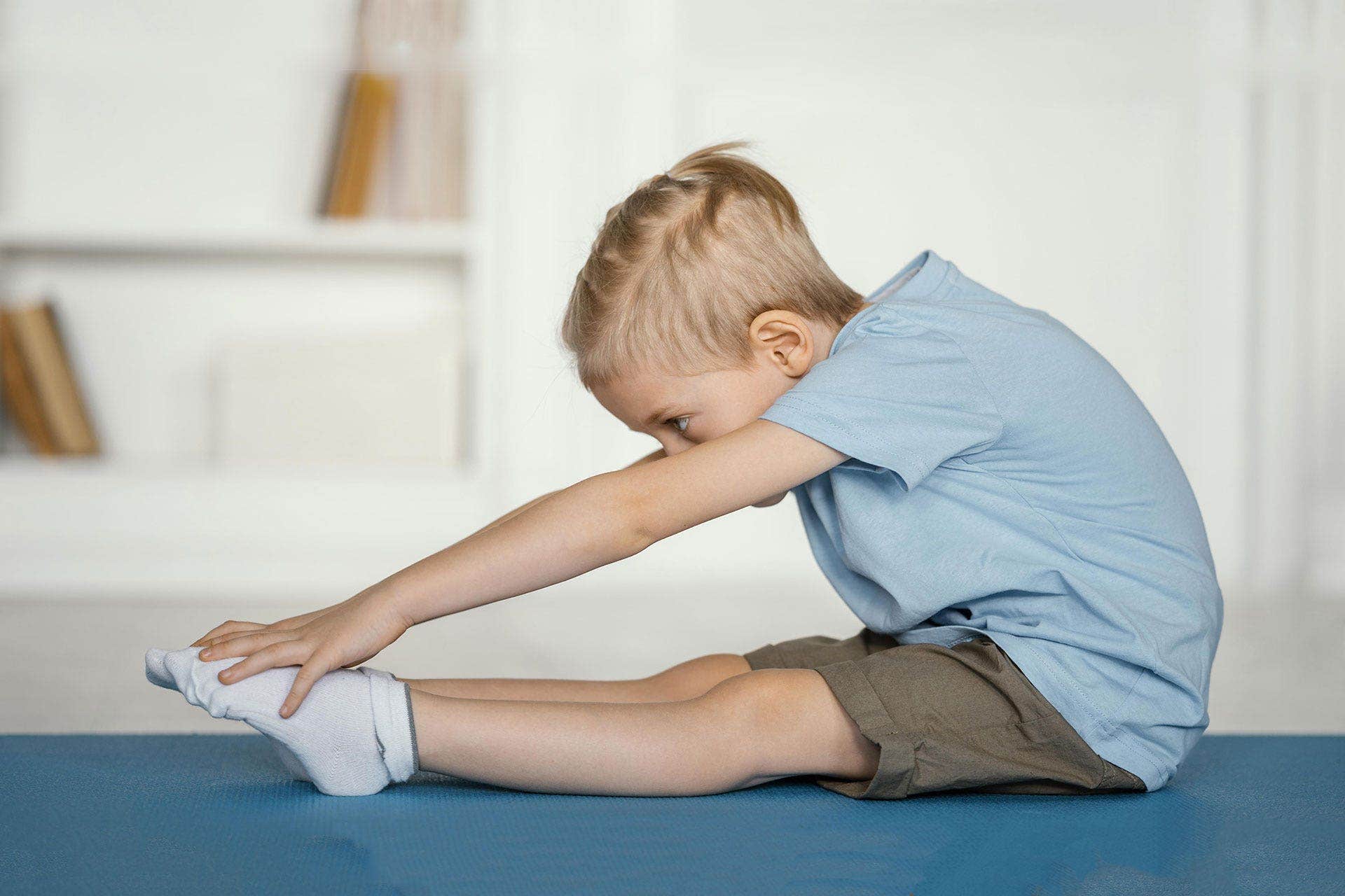 Yoga- og gymnastikmåtte med dreng der strækker ud